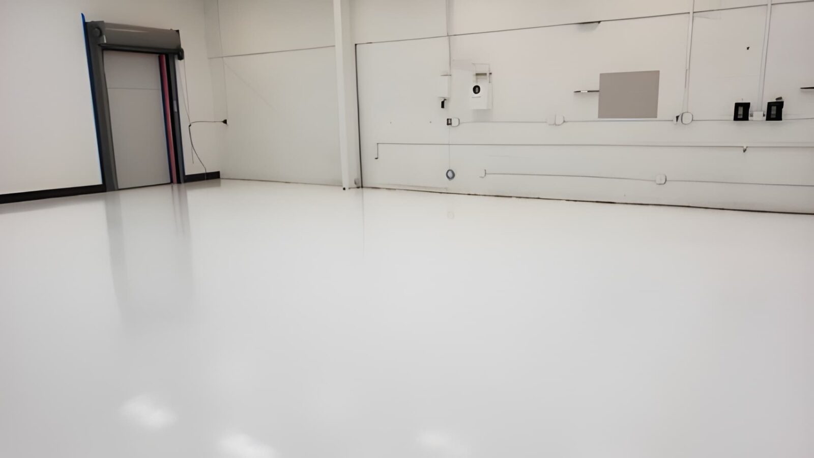 Newly installed high-gloss seamless white epoxy flooring in a clean industrial facility